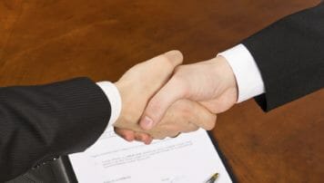 Businessmen hand shake after signing the agreement.